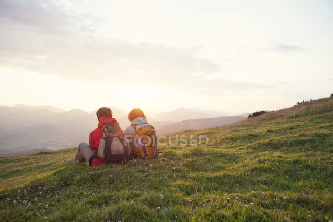 Autriche, Tyrol, Unterberghorn, deux randonneurs se reposant dans un paysage alpin au lever du soleil — Photo de stock