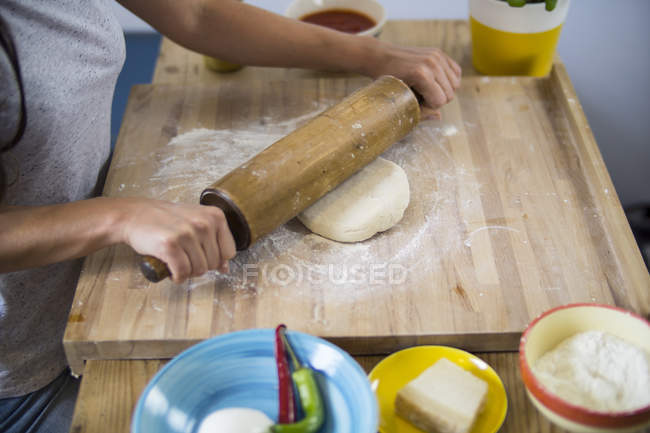 Frau bereitet Pizzateig in Küche zu — Stockfoto