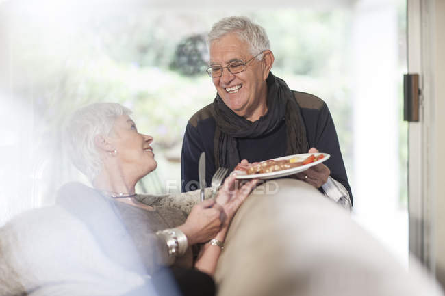 Senior couple with plate of food at home — Stock Photo