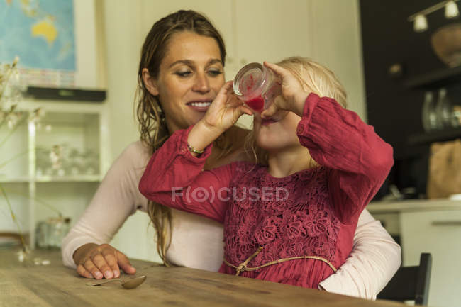 Mère regardant sa fille boire du verre — Photo de stock