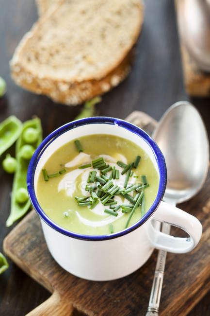 Vista da vicino della tazza di smalto di zuppa di piselli con erba cipollina — Foto stock