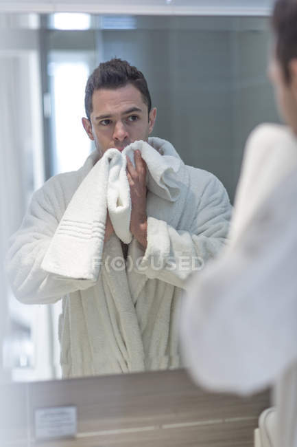 Imagem espelhada do homem observando a si mesmo enquanto secava o rosto com toalha — Fotografia de Stock