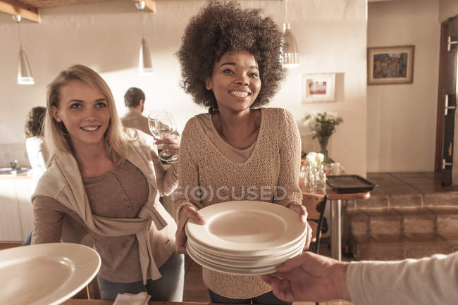 Amici che apparecchiano una tavola insieme alla cucina moderna — Foto stock