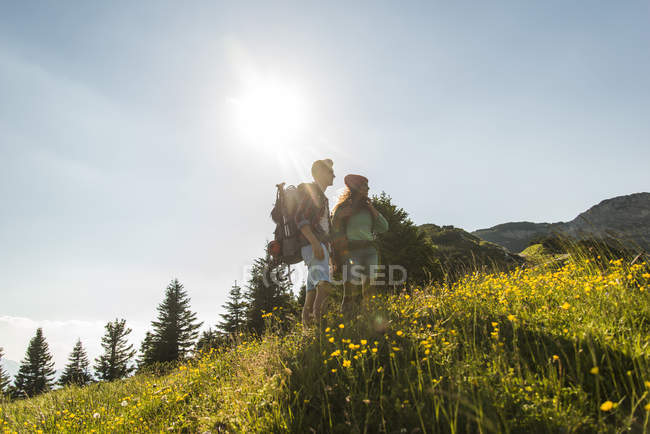 Austria, Tyrol, Tannheimer Tal, young couple standing on alpine meadow — Stock Photo