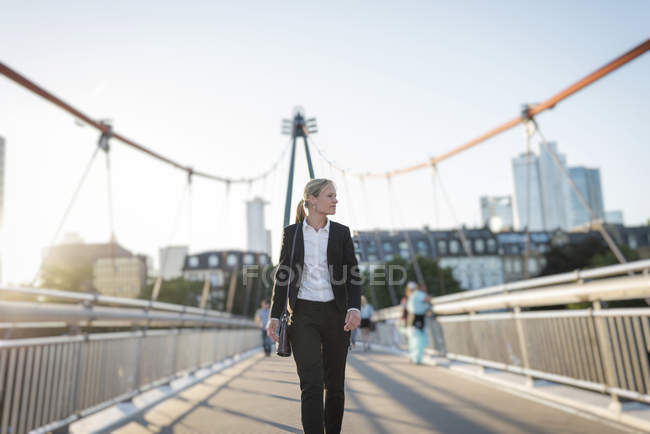 Businesswoman walking on a bridge at twilight — Stock Photo