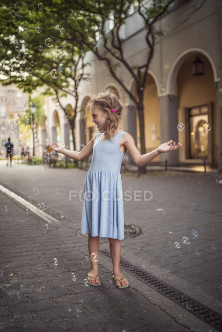 Menina brincando com bolhas de sabão na rua — Fotografia de Stock