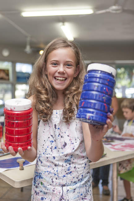 Portrait of smiling girl in an art class holding bottles with paints — Stock Photo