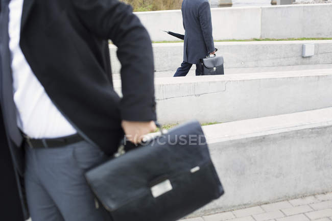 Uomini d'affari che camminano con valigette — Foto stock