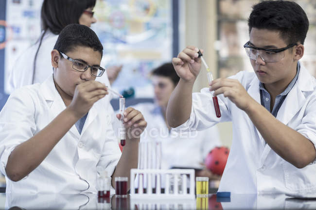 Students in chemistry class pipetting liquid into test tube — Stock Photo