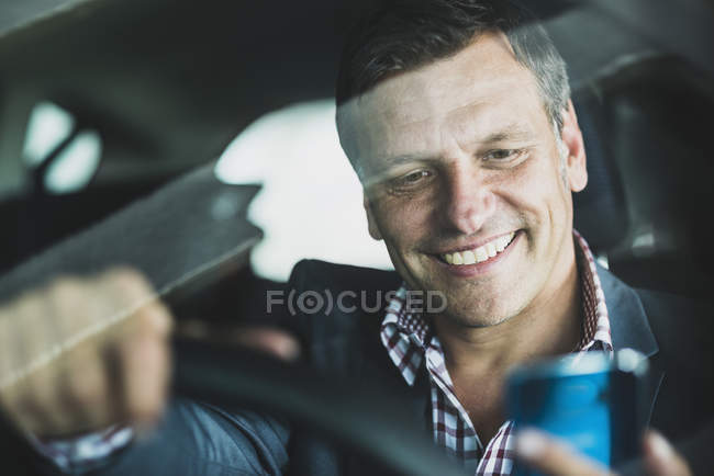 Uomo d'affari maturo che utilizza lo smartphone in auto — Foto stock