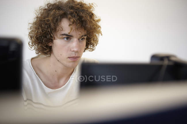 Jeune homme au bureau regardant l'écran d'ordinateur — Photo de stock
