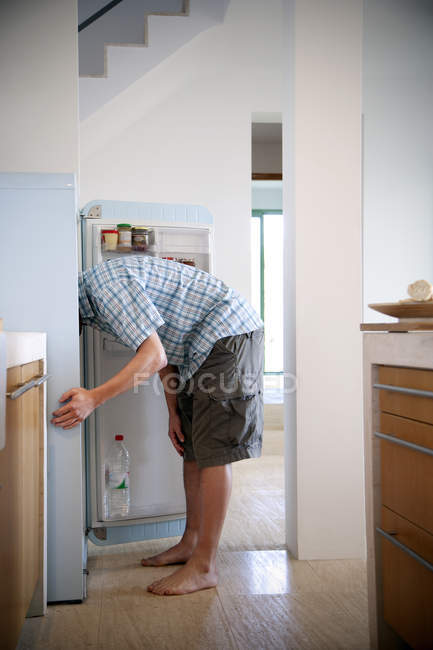 Un joven parado en la cocina buscando algo en el refrigerador — Stock Photo