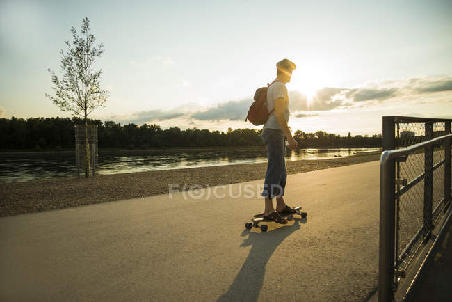 Uomo in piedi sullo skateboard al crepuscolo della sera — Foto stock