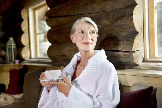 Sorrindo mulher idosa em roupão de banho bebendo chá — Fotografia de Stock