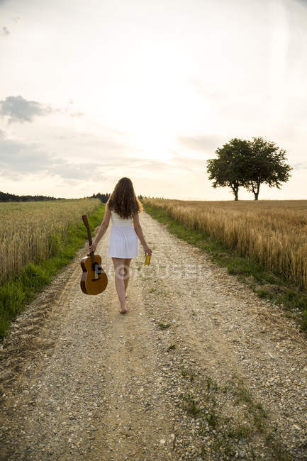 Mulher andando com guitarra em campo — Fotografia de Stock