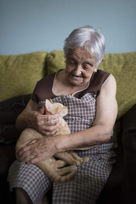 Femme âgée caressant chaton couché sur ses genoux — Photo de stock