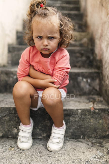 Ritratto di bambina seduta su gradini che fa male alla bocca — Foto stock