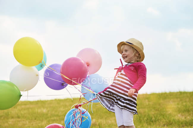 Девочка с воздушными шарами на лугу — стоковое фото