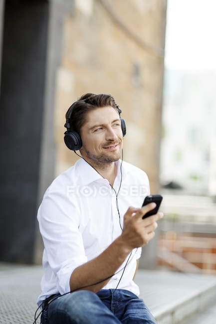 Portrait of smiling man hearing music with MP3 Player and headphones — Stock Photo