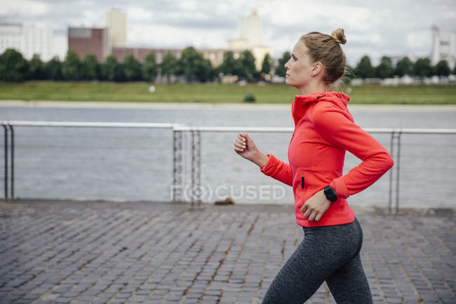 Germany, Cologne, young woman jogging at River Rhine — Stock Photo