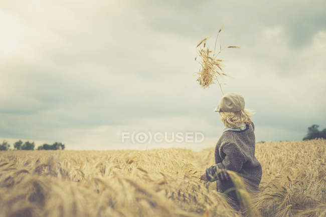 Little boy standing in a field throwing spikes in the air — Stock Photo