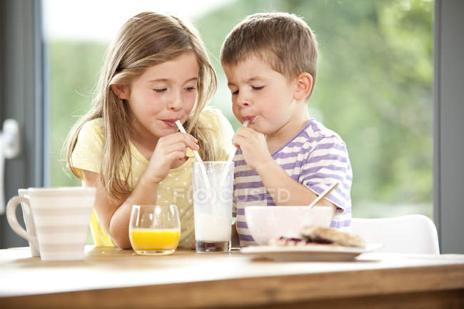 Brother and sister sharing glass of milk — Stock Photo
