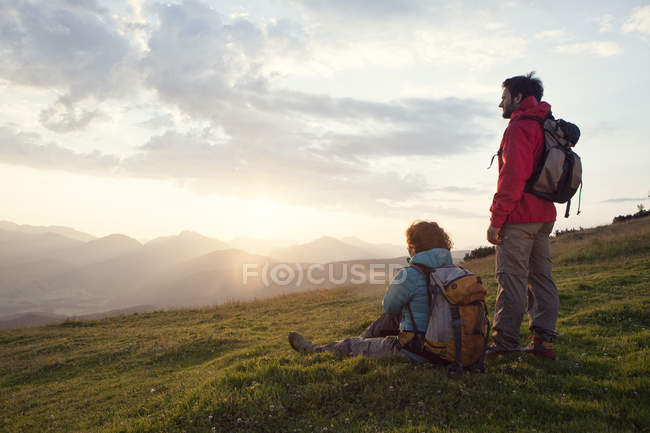 Österreich, Tirol, Unterberghorn, zwei Wanderer ruhen sich bei Sonnenaufgang in alpiner Landschaft aus — Stockfoto
