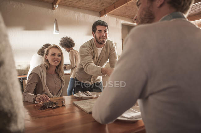 Amis mettre une table ensemble à la cuisine moderne — Photo de stock