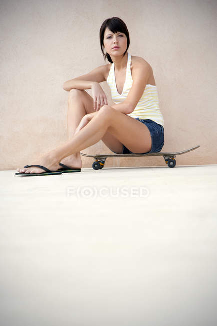 Jovem mulher sentada em seu longboard — Fotografia de Stock