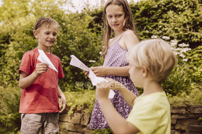 Tre bambini che giocano con aerei di carta in giardino — Foto stock