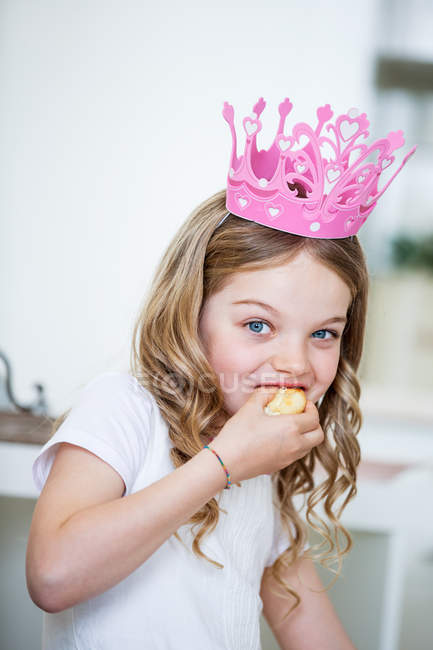 Menina vestindo rosa coroa comer bolo — Fotografia de Stock