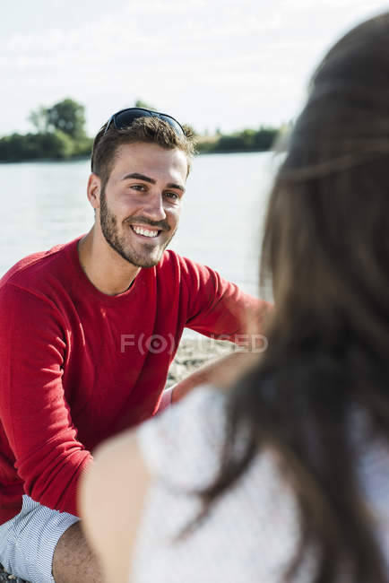 Giovane uomo sorridente alla donna sul lungofiume — Foto stock
