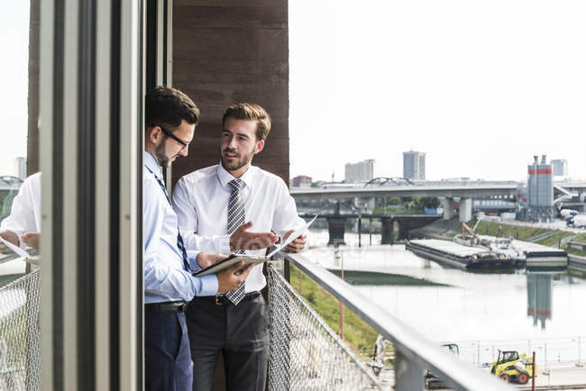 Zwei junge Geschäftsleute mit Dokumenten und digitalem Tablet diskutieren auf Balkon — Stockfoto