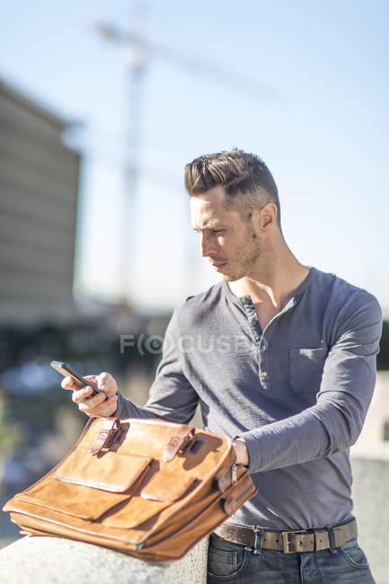 Hombre en la ciudad con maletín y celular - foto de stock