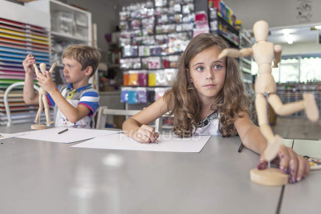 Portrait of girl and boy in an art class by the table with lay figure — Stock Photo