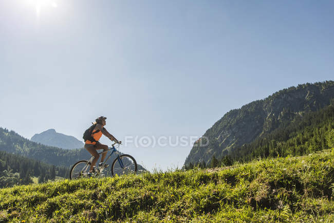 Austria, Tirolo, Valle di Tannheim, giovane donna in mountain bike nel paesaggio alpino — Foto stock