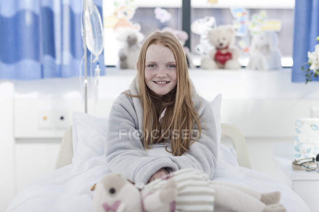 Портрет посміхається дівчина з рудим волоссям в лікарняному ліжку — стокове фото