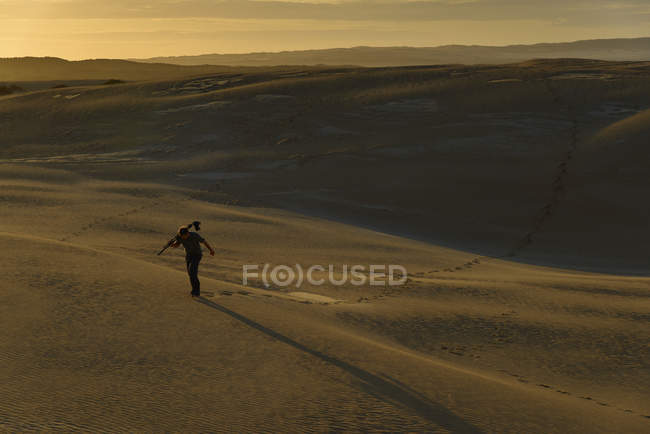 Australia Meridionale, uomo con treppiede e macchina fotografica che cammina tra dune di sabbia al crepuscolo — Foto stock