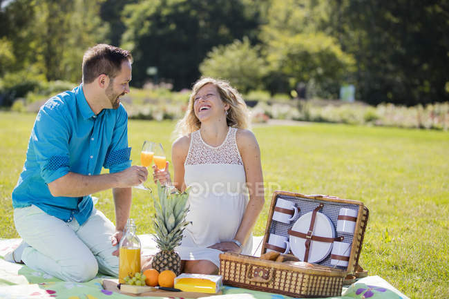 Happy couple having a picnic in park, pregnant woman — Stock Photo
