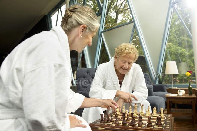 Pareja mayor en albornoces jugando ajedrez - foto de stock