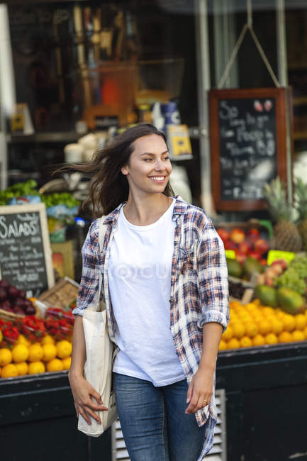 Smiling young woman at greengrocer's shop — Stock Photo