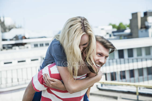 Germany, Cologne, young man giving his girlfriend a piggy back — Stock Photo