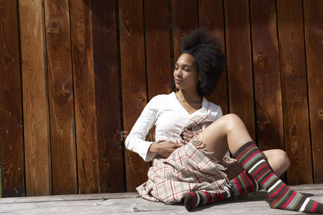 Sunbathing jovem mulher encostada na parede de madeira — Fotografia de Stock