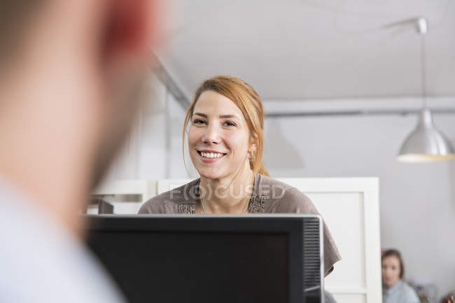 Portrait of smiling young woman with colleagues in office — Stock Photo
