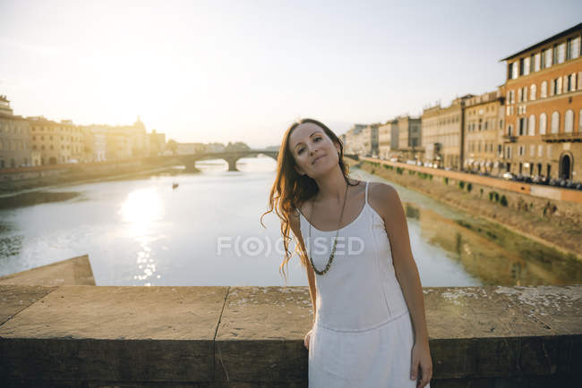 Italia, Firenze, ritratto di donna vestita di bianco in piedi su un ponte al tramonto — Foto stock