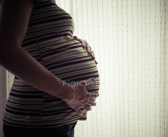Pregnant woman against bright window — Stock Photo