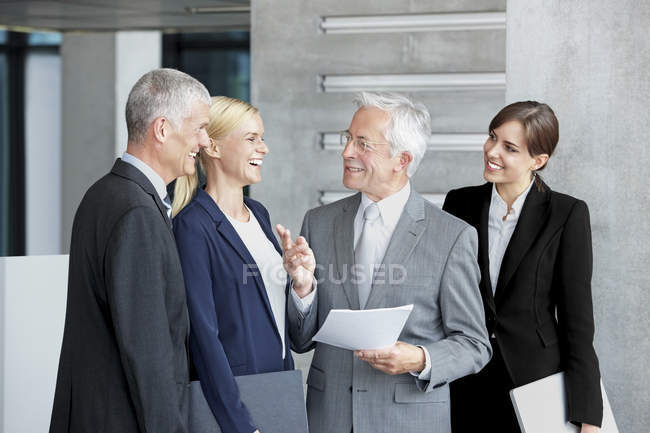 Compañeros de negocios felices discutiendo lobby de oficina de documentos - foto de stock