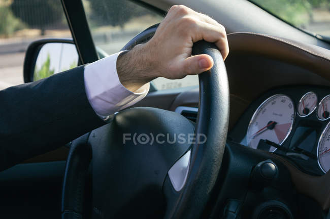 Hand of a businessman on steering wheel of his car — Stock Photo