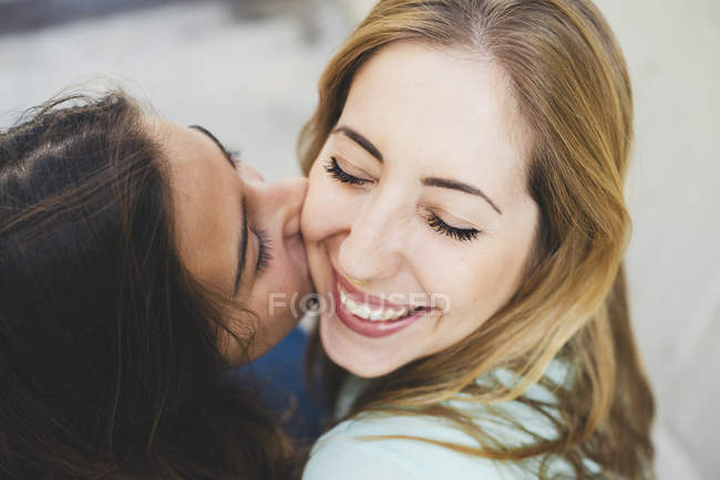 Ragazza baciare giovane donna sulla guancia — Foto stock