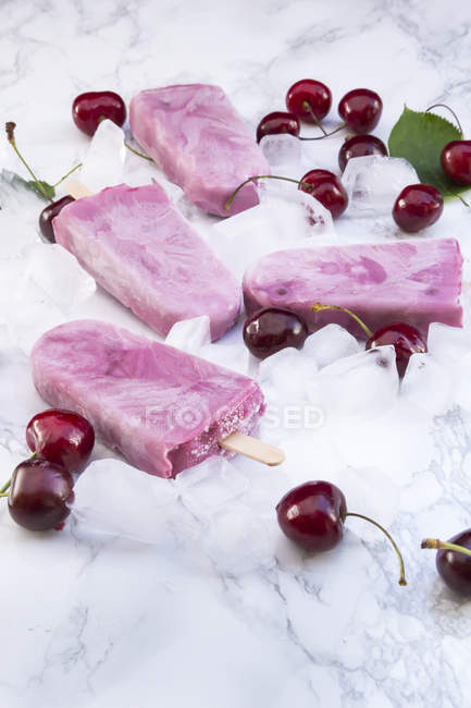 Helados de yogur de cereza y cerezas sobre mármol blanco - foto de stock
